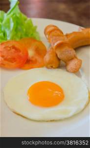Plate of breakfast with fried egg, ham, sausage and fresh vegetable