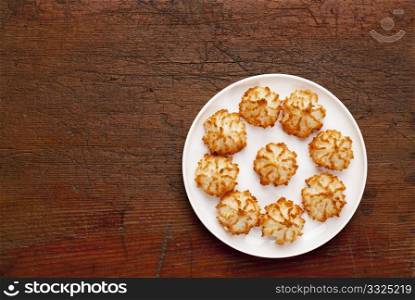 plate of coconut macaroon cookies on old scratched wooden table, top view