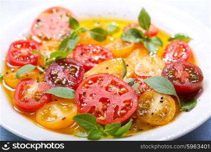 plate of colorful tomatoes with oil and basil