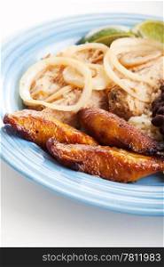 Plate of Cuban food, with fried sweet plaintains, roast port, and black beans & rice. Focus on the plaintains.