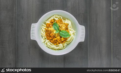 Plate of delicious spaghetti bolognese . Plate of delicious spaghetti bolognese with savory minced beef and tomato sauce garnished with basil, overhead view