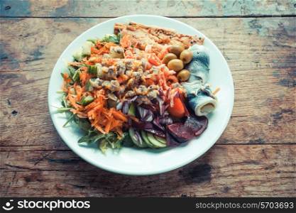 Plate of fish and salad on a wooden table