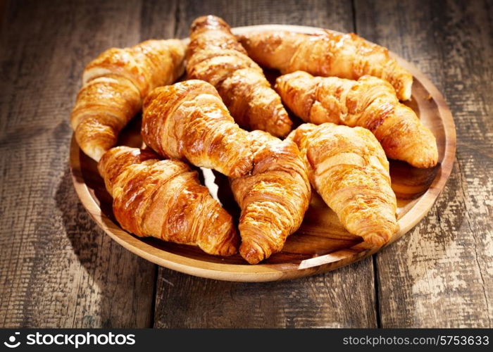 plate of fresh croissants on wooden table