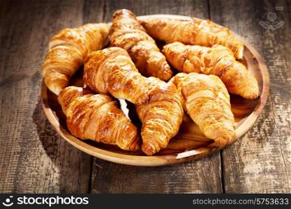 plate of fresh croissants on wooden table