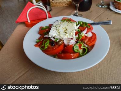 Plate of Greek salad with tomatoes, onions. Plate of Greek salad with tomatoes, onions, peppers, feta, bread.