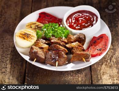 plate of grilled meat with vegetables on wooden table