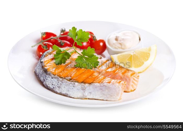 plate of grilled salmon steak with vegetables on white background