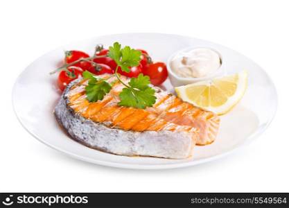 plate of grilled salmon steak with vegetables on white background