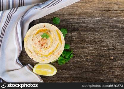 Plate of hummus on wooden table with copy space, top view. Plate of hummus