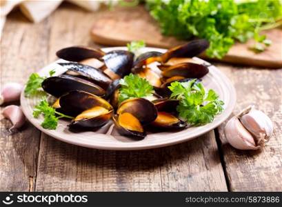 plate of mussels with parsley on wooden table