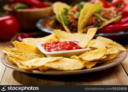 plate of nachos with salsa on wooden table