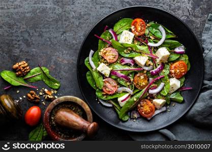 plate of nutritious simple salad with chard, walnuts, soft cheese, onions and oil, top view, space for text