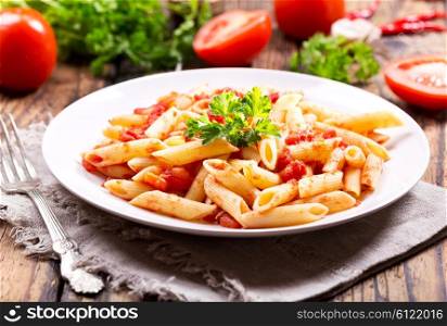plate of pasta with tomato sauce on wooden table