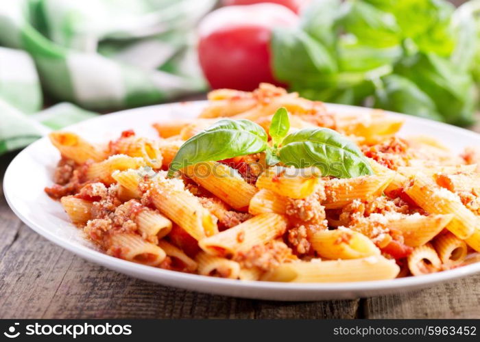 plate of penne pasta bolognese on wooden table