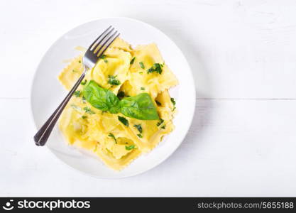 plate of ravioli with basil on wooden table