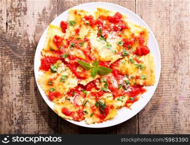 plate of ravioli with tomato sauce on wooden background