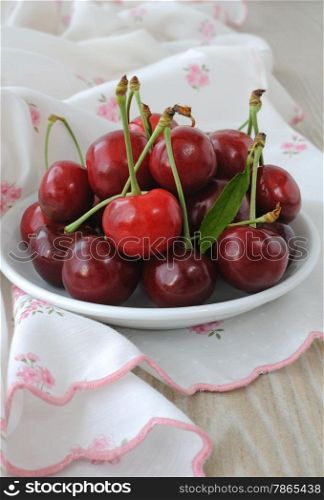 plate of ripe cherries on the table with a napkin