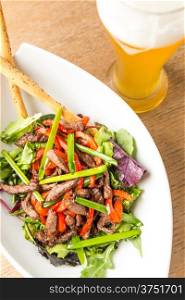 plate of salad from meat with vegetables and glass light bear