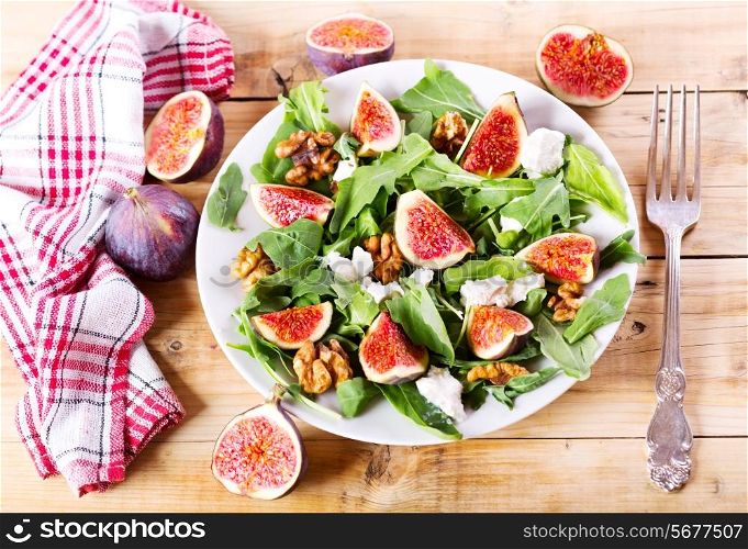 plate of salad with figs on wooden table