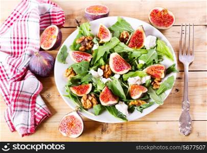 plate of salad with figs on wooden table