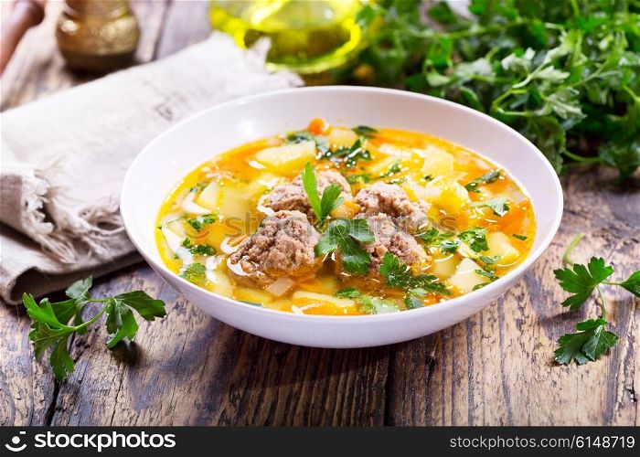 plate of soup with meatballs on wooden table