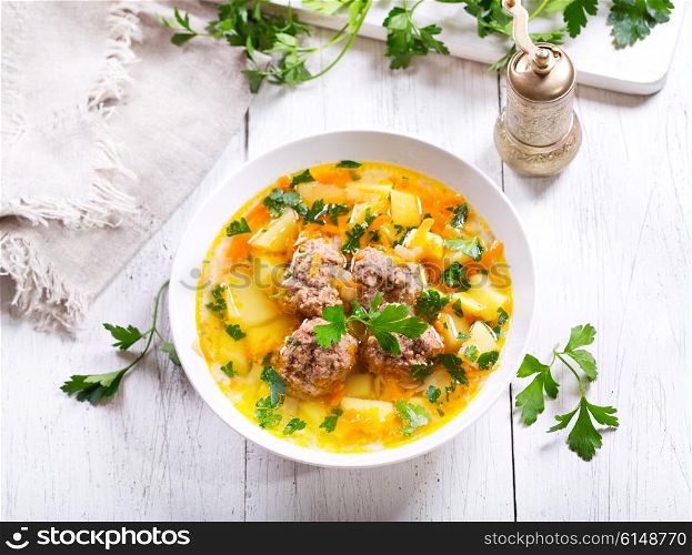 plate of soup with meatballs on wooden table