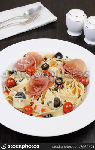 plate of spaghetti with jamon, tomatoes, olives and parmesan