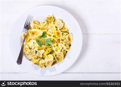 plate of tortellini with parsley on wooden table