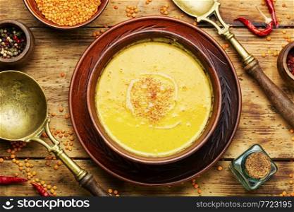 Plate of vegetarian red lentil soup on wooden table. Rustic soup with lentils