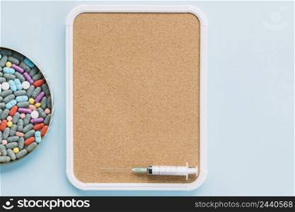 plate with colorful pills syringe cork tray against blue backdrop