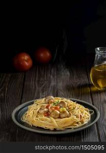 Plate with cooked dinner - pasta with cheese, mushrooms and vegetables, dark wooden background. Steam rises above the dish. Close-up, shallow depth of field. Vegetarian lunch concept