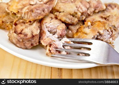 Plate with fried brains and fork on a wooden boards background