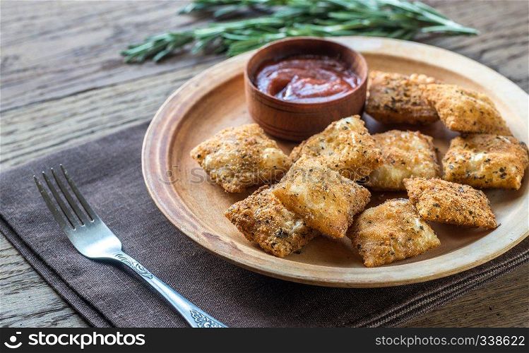 Plate with fried ravioli on the wooden board