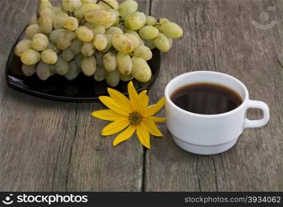 plate with grapes, a cup of coffee and a yellow flower, a still life on an old table, a subject fruit and drinks