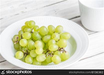 Plate with green grapes on a wooden table