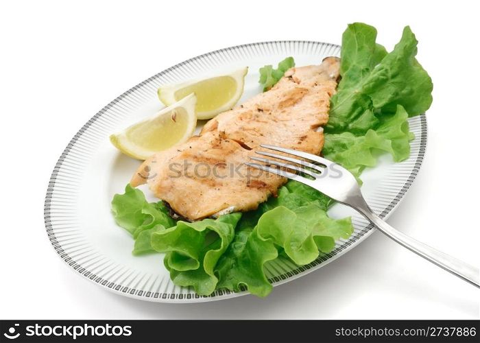 plate with grilled salmon trout fillet, lettuce and lemon isolated on white background with clipping path