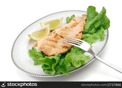 plate with grilled salmon trout fillet, lettuce and lemon isolated on white background with clipping path