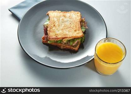 plate with grilled sandwich and orange juice on white table. plate with grilled sandwich and orange juice
