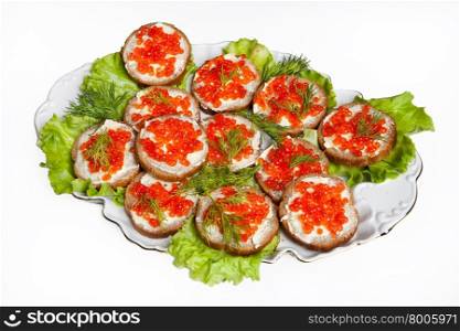 Plate with little sandwiches with red caviar and vegetables