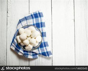 Plate with mozzarella on a napkin. On a white wooden background.. Plate with mozzarella on a napkin.