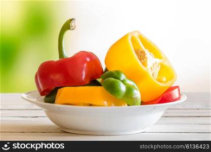 Plate with pepper fruit on a wooden table in a garden