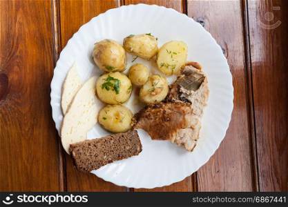 Plate with potato, cheese, meat and bread on the wooden background