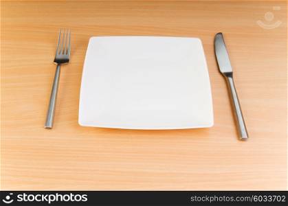 Plate with utensils on wooden table