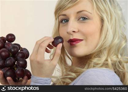 platinum blonde eating red grapes