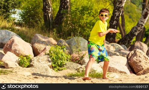 Play and fun concept. Little playful enjoyable boy kid throwing frisbee disc. Male child having fun playing outdoor on beach.. Little boy playing with frisbee disc.