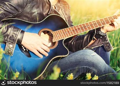 Play the acoustic guitar in a summer meadow in the sun-