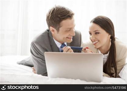 Playful business couple with laptop in hotel room