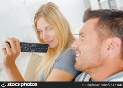Playful couple fighting over the TV remote