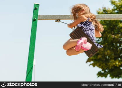 Playful crazy girl on swing.. Craziness and freedom. Young summer girl playing on swing-set outdoor. Crazy playful child swinging very high to touch the sky.
