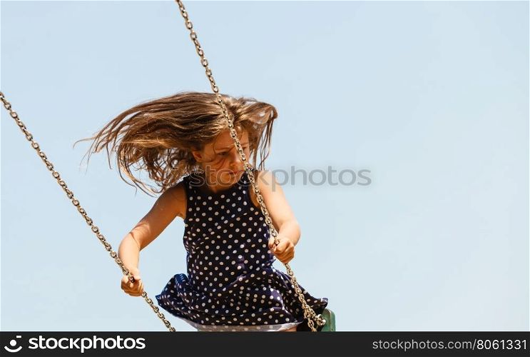 Playful crazy girl on swing.. Craziness and freedom. Young summer girl playing on swing-set outdoor. Crazy playful child swinging very high to touch the sky.